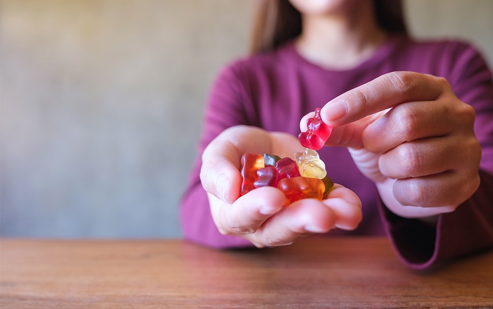 imagem de uma mulher segurando um tipo de suplementação em gummy.