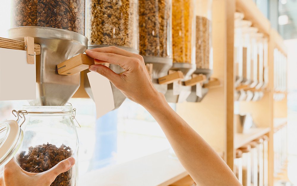 Imagem de uma cliente comprando granola em uma loja com diversos alimentos naturais.