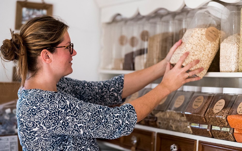 Mulher organizando os produtos naturais da sua loja de produtos naturais.